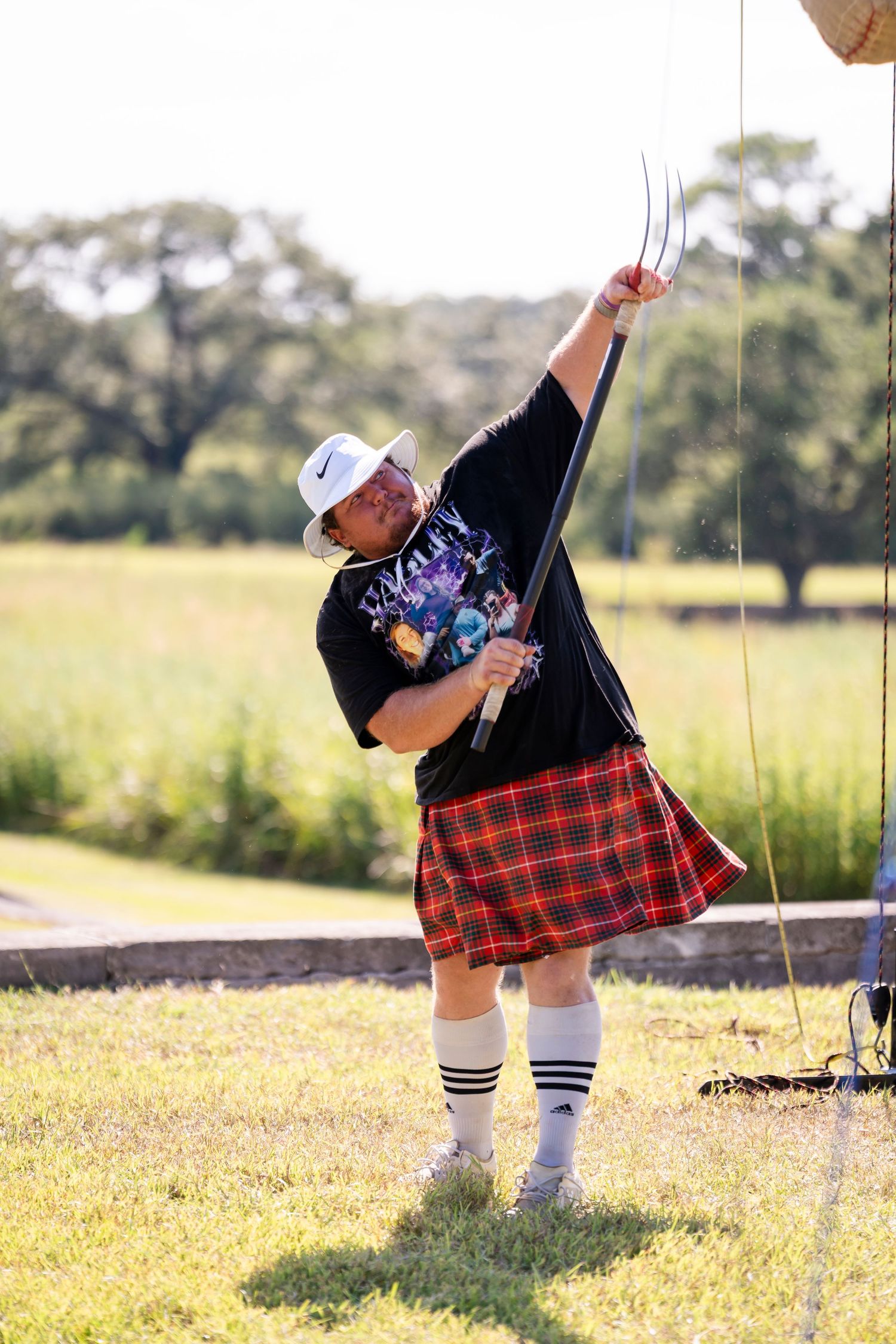 Three sequential photos show someone in a plaid kilt swinging on a rope swing in a sunny meadow.