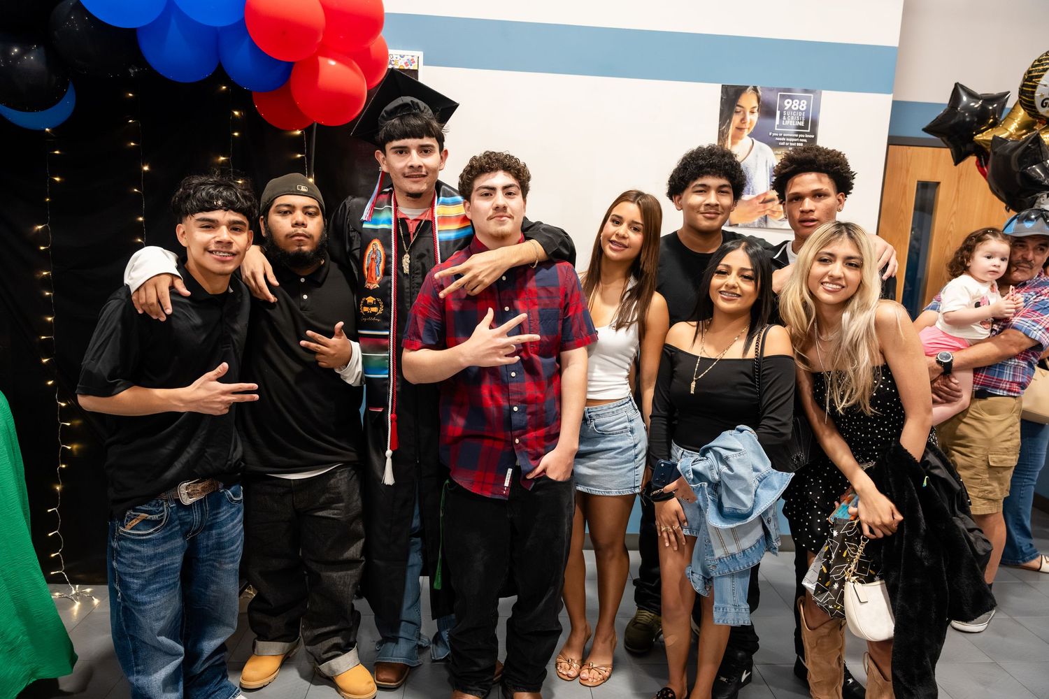 Group of friends and family celebrating a graduation party with balloons and festive decorations indoors.