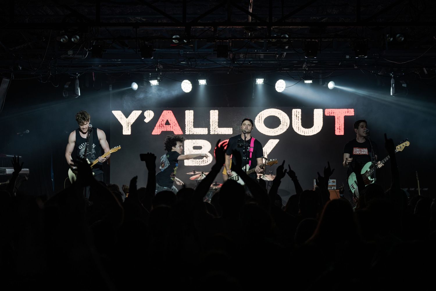 Y'all Out Boy tribute band performing live on stage with bright lights and an energetic crowd.