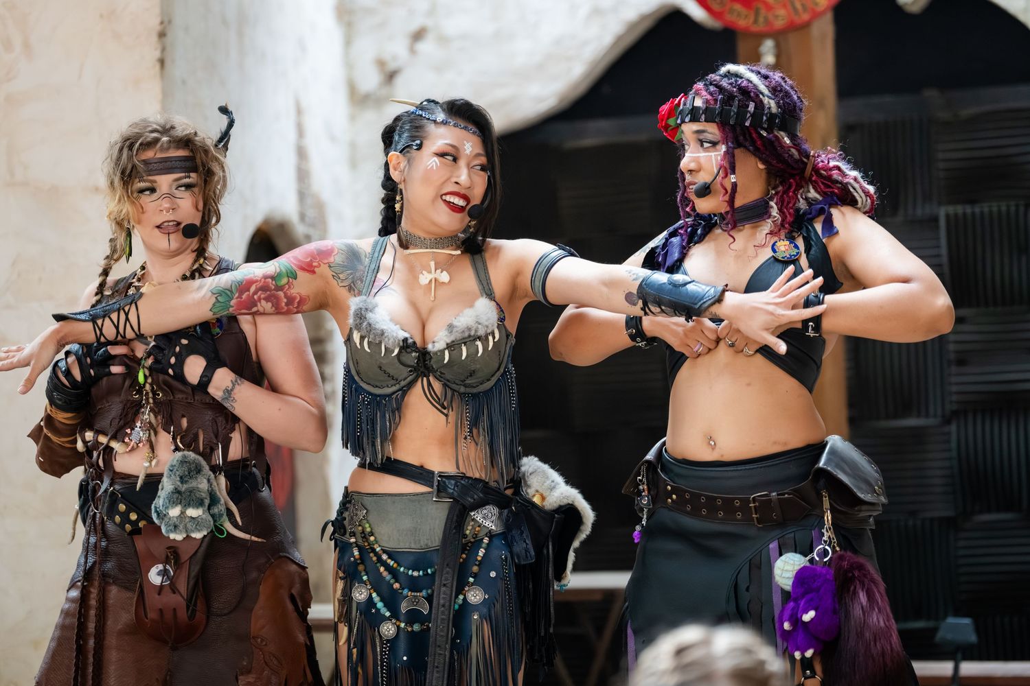 Cosplayers in post-apocalyptic steampunk costumes pose with prop weapons at a convention event.