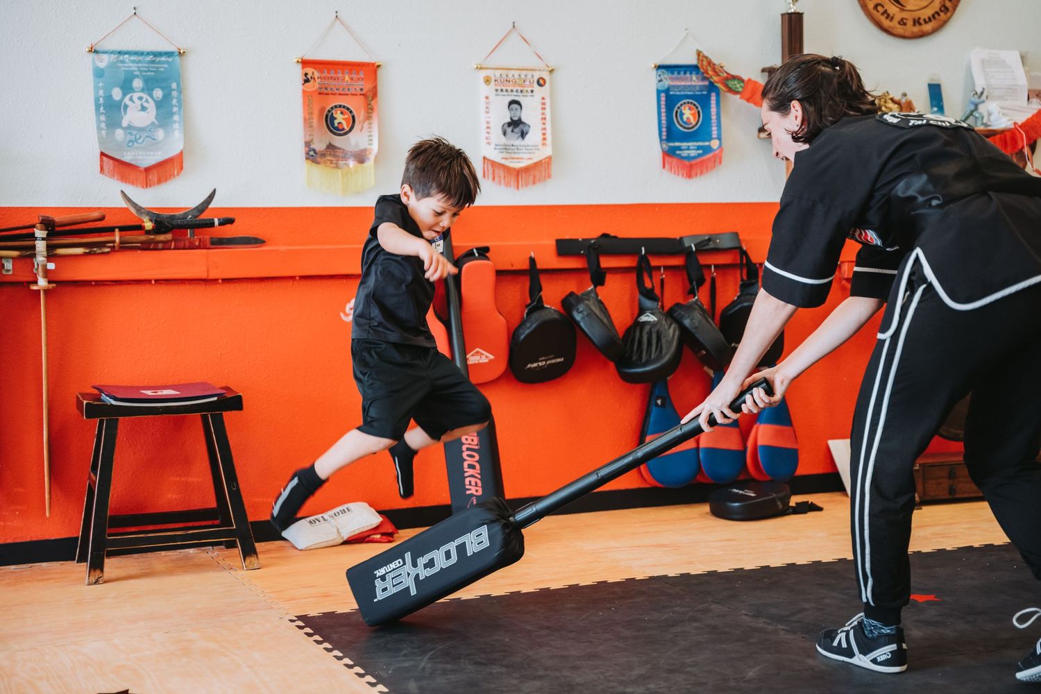 Student practicing balance exercises with instructor in martial arts studio.