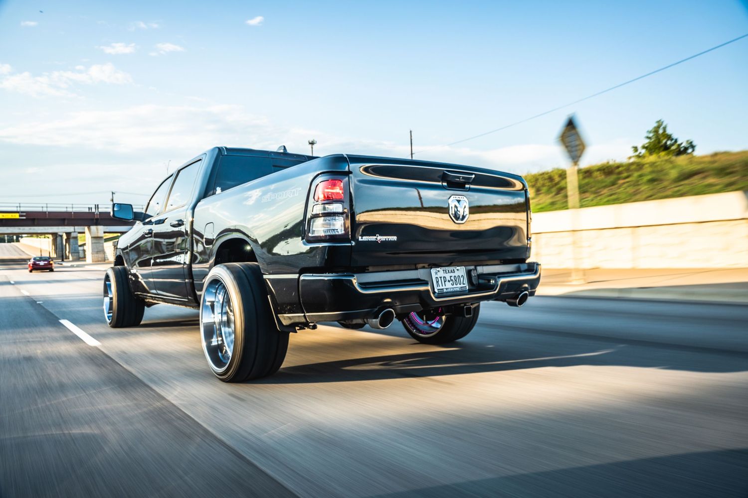 Lifted black Chevrolet pickup truck with custom wheels driving on highway.