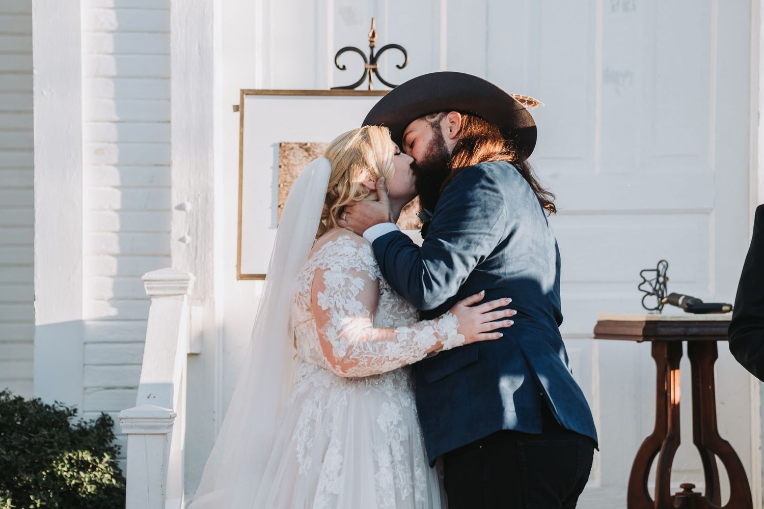 A tender wedding moment shared between newlyweds in front of a white building.