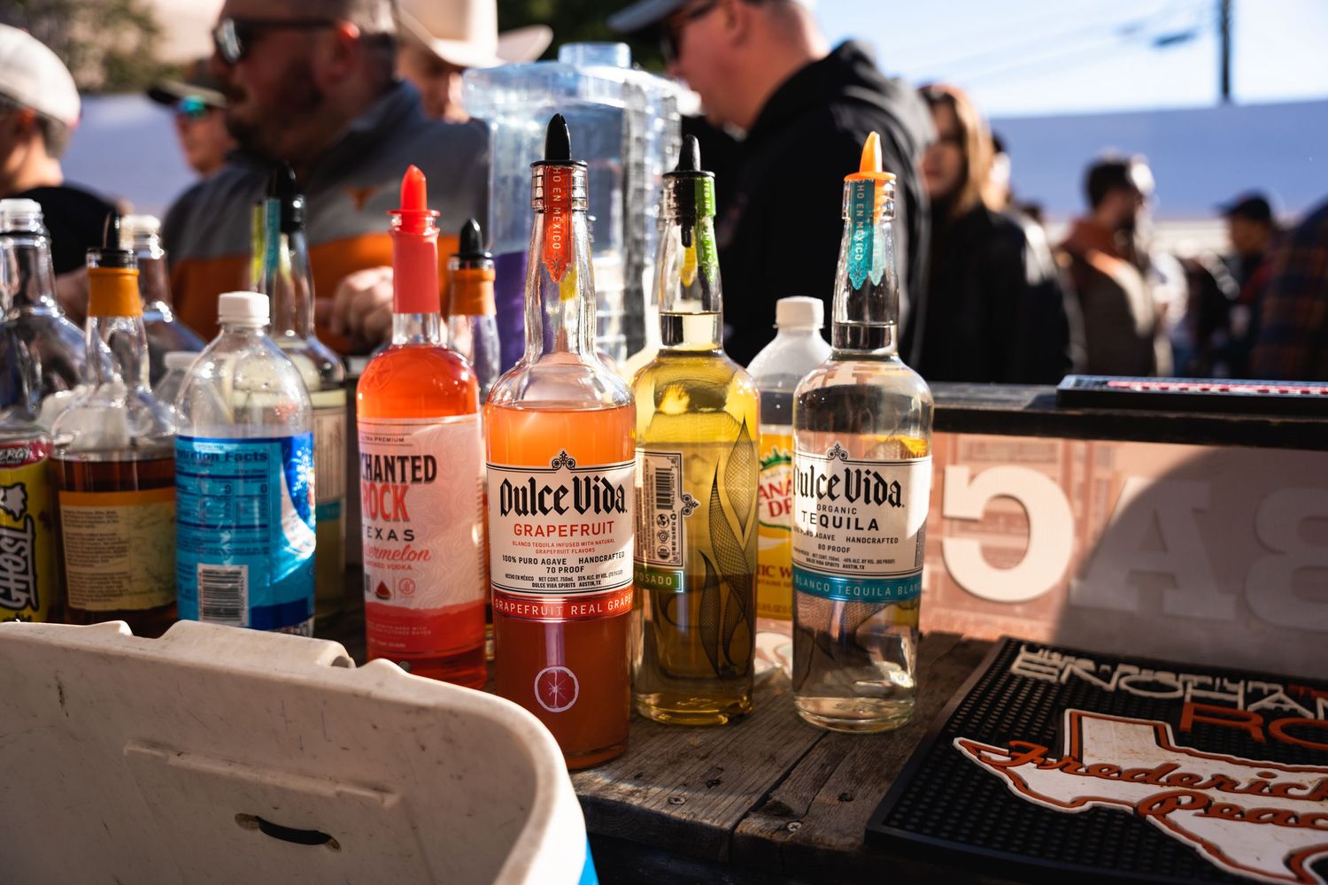 Array of liquor bottles displayed on an outdoor bar counter in natural lighting.