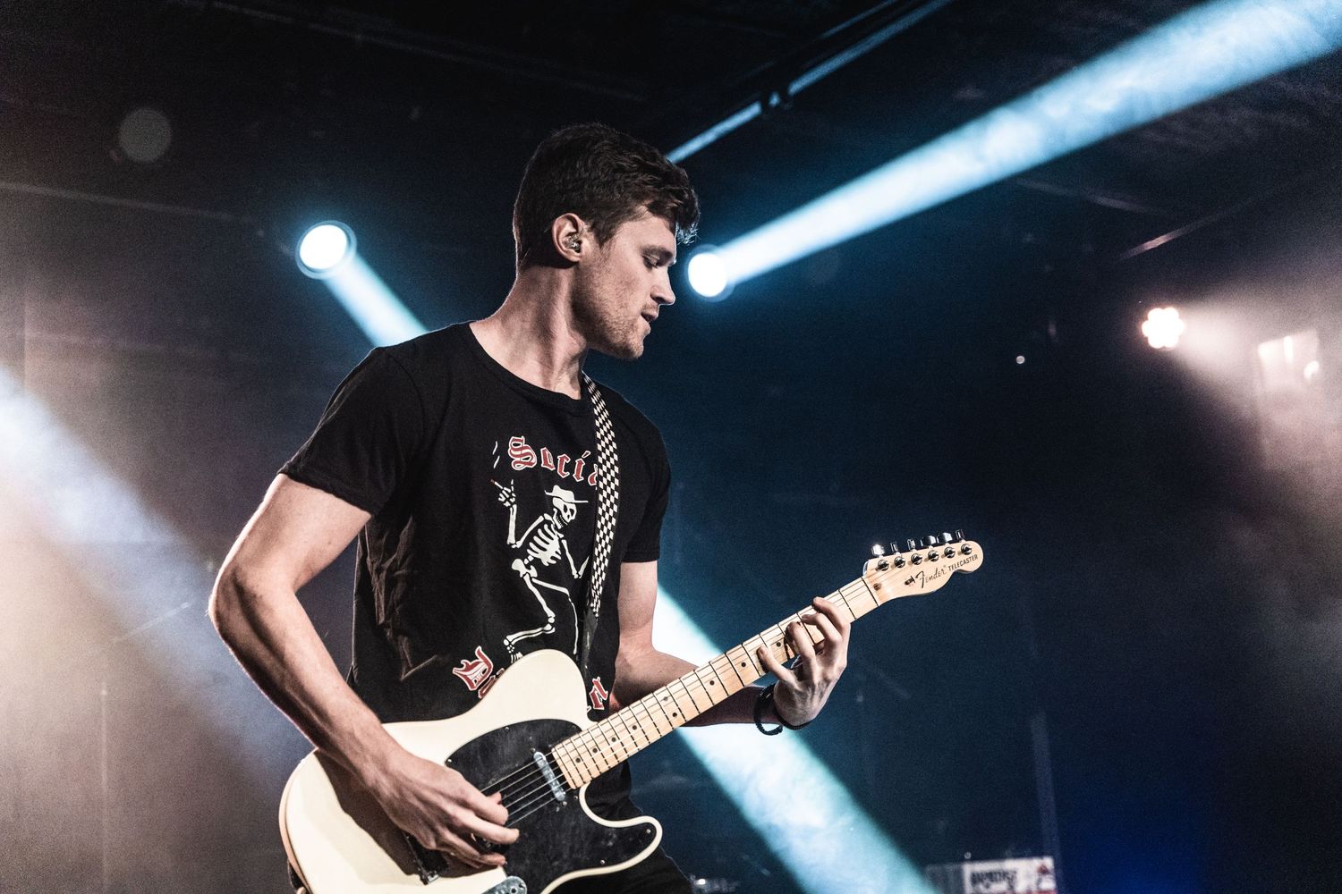 A guitarist performing on stage with dramatic blue lighting effects.