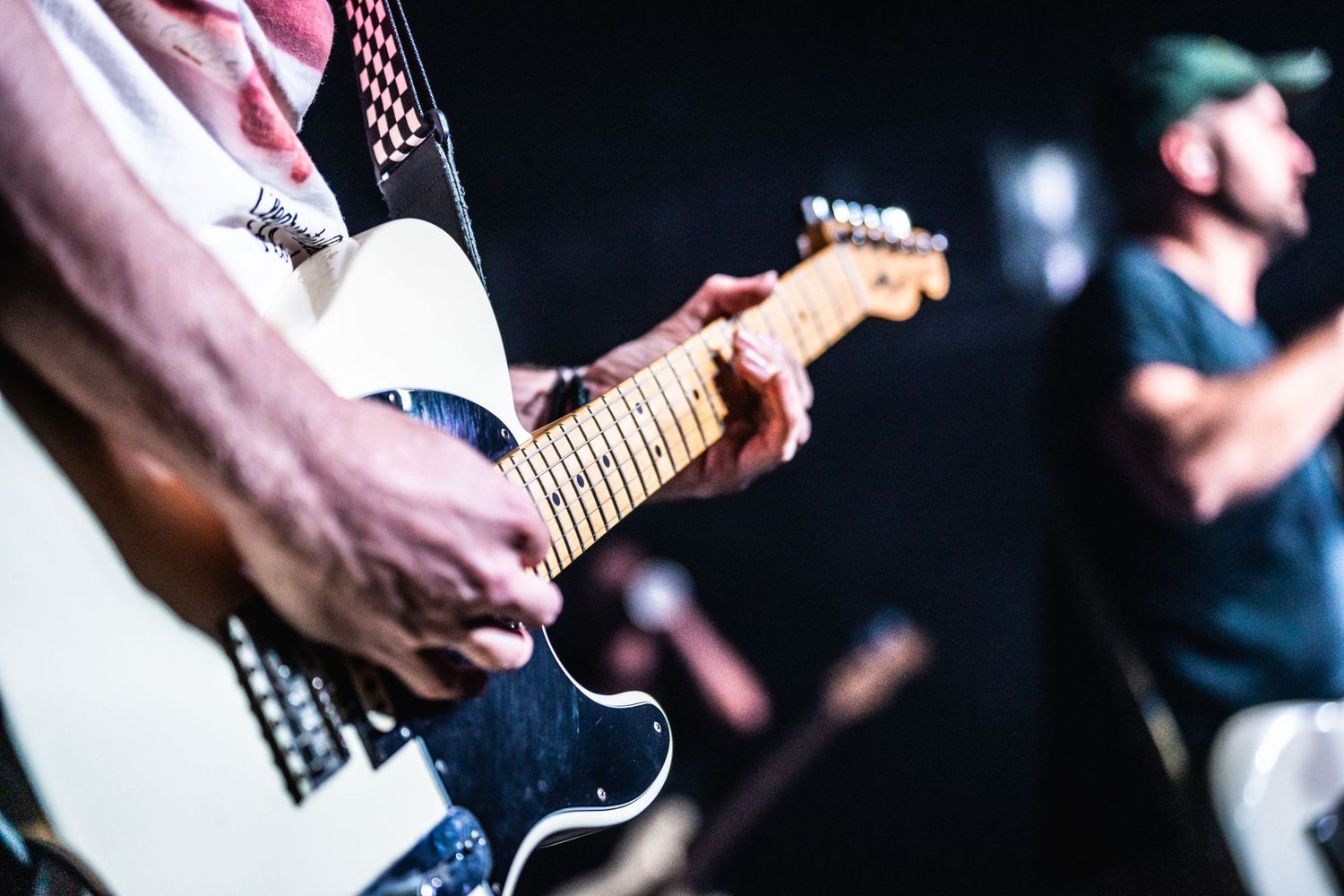 Close-up shot of guitarist's hands playing electric guitar during live performance.