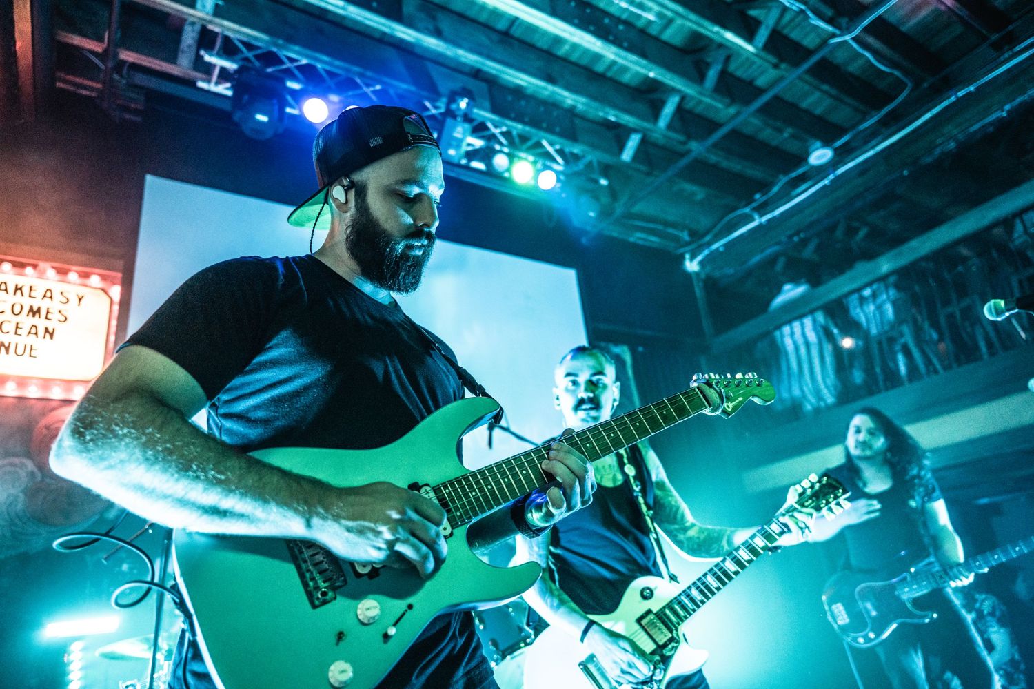 Musicians playing guitars under blue stage lighting during live performance.