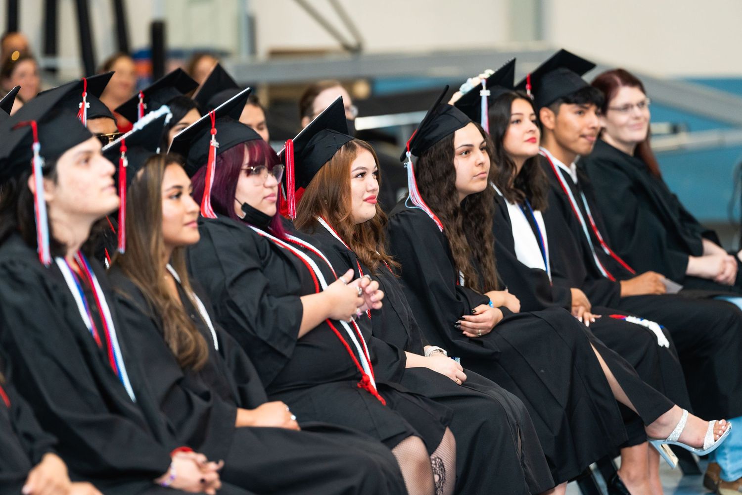 A group of graduates in black caps and gowns seated during a commencement ceremony.