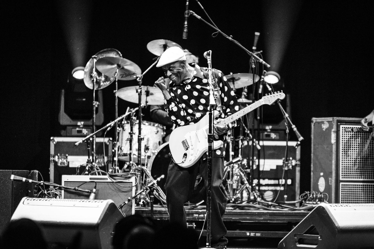 Black and white concert photo of band performing with dramatic stage setup.
