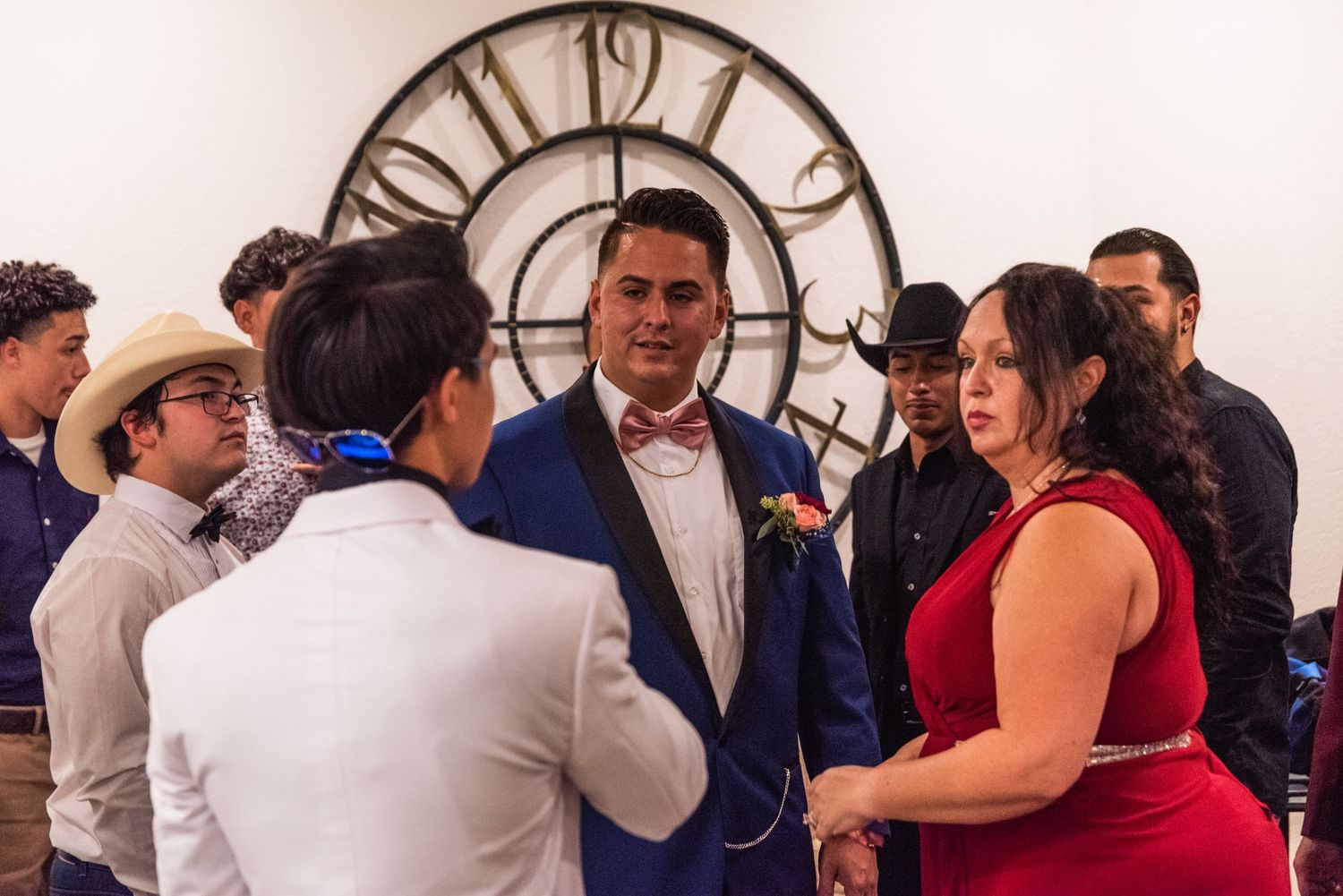 A group gathering around a large decorative clock during a wedding celebration.