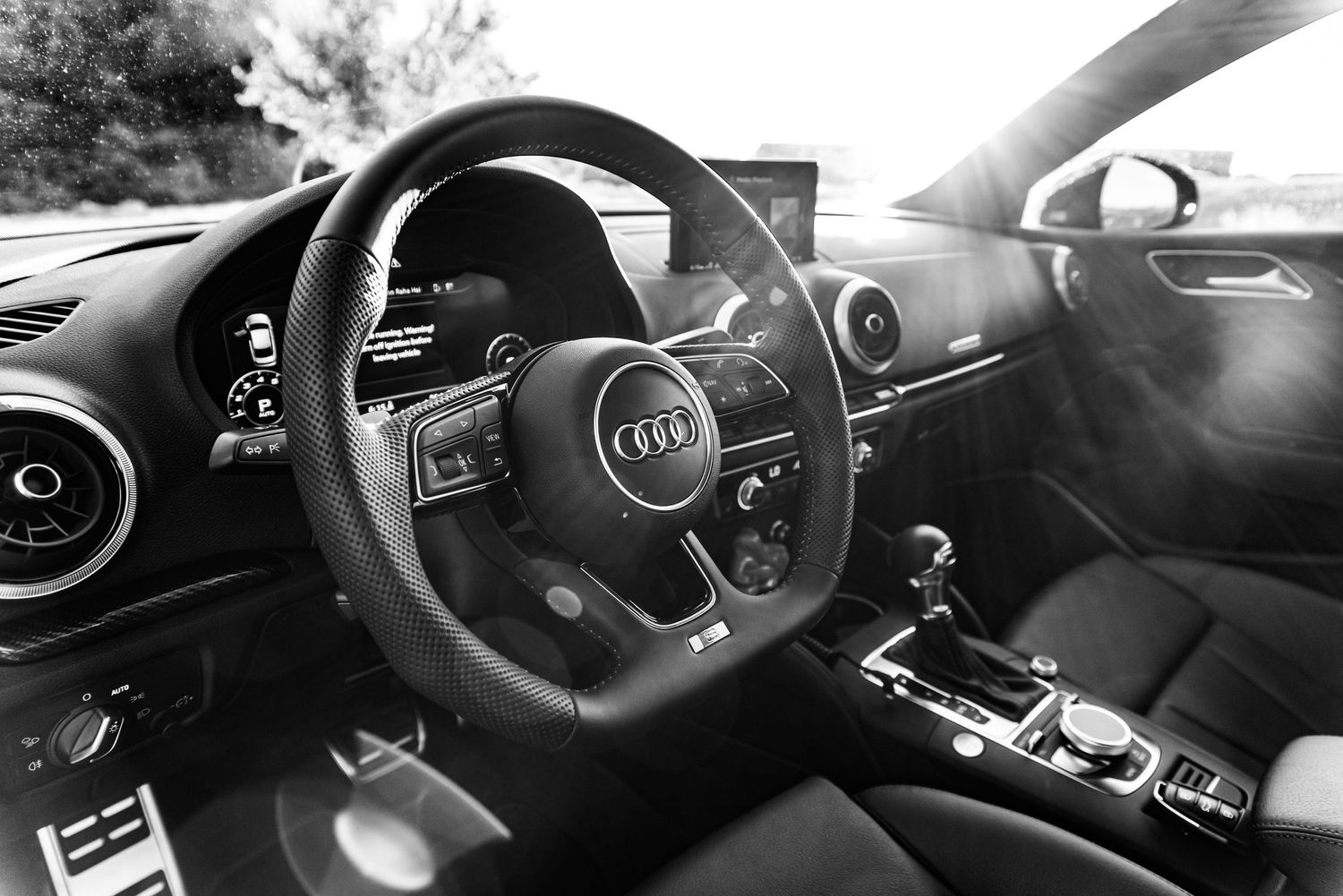 Black and white interior shot of an Audi vehicle dashboard and steering wheel.