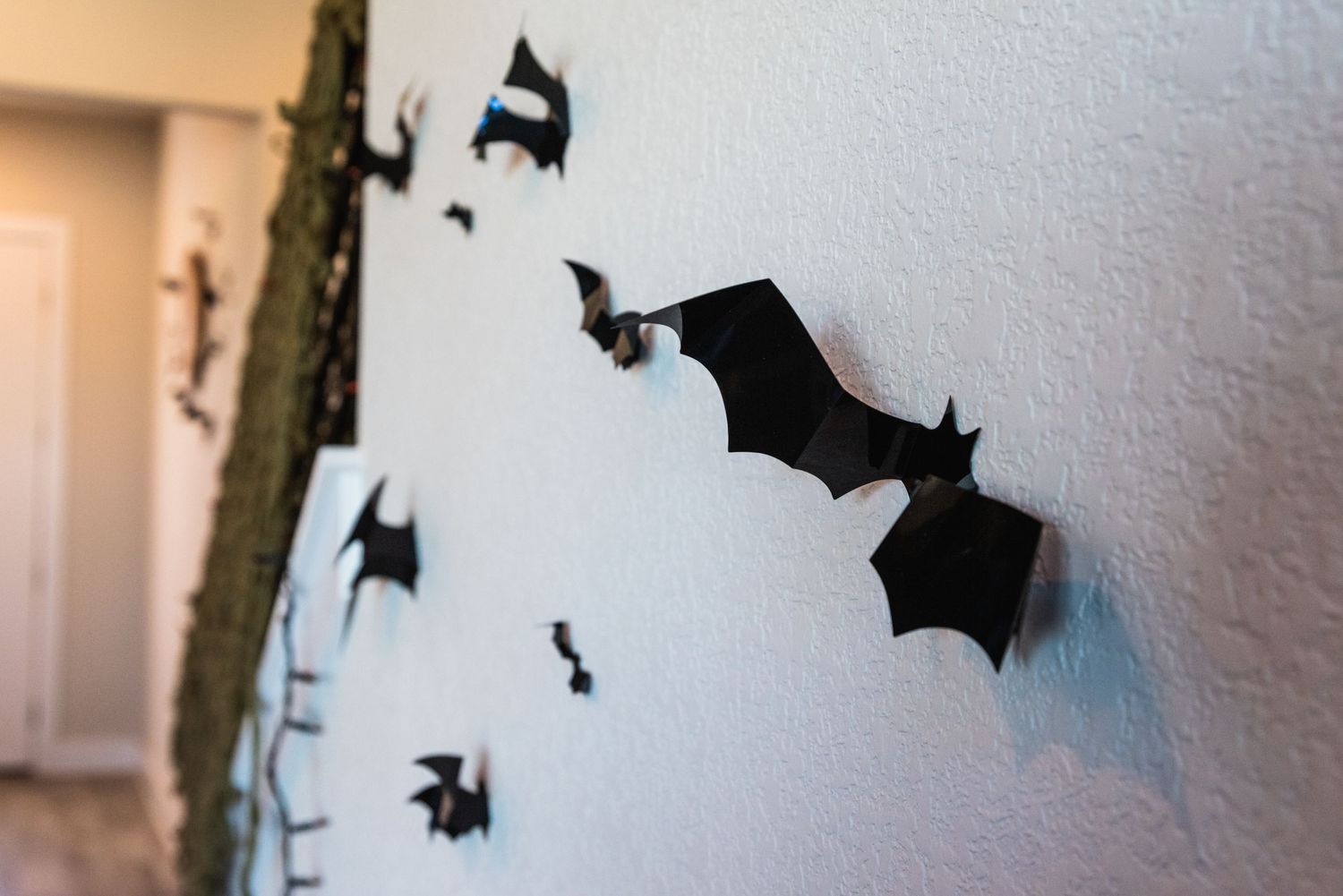Black paper bats decoratively arranged on a white wall creating spooky Halloween decor.