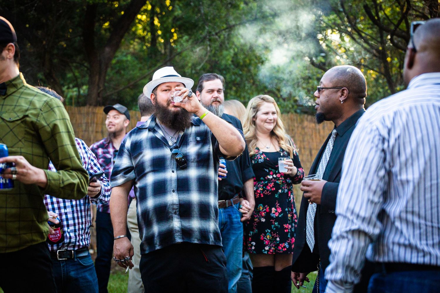 Wedding guests enjoying drinks and conversation at an outdoor garden reception during golden hour.