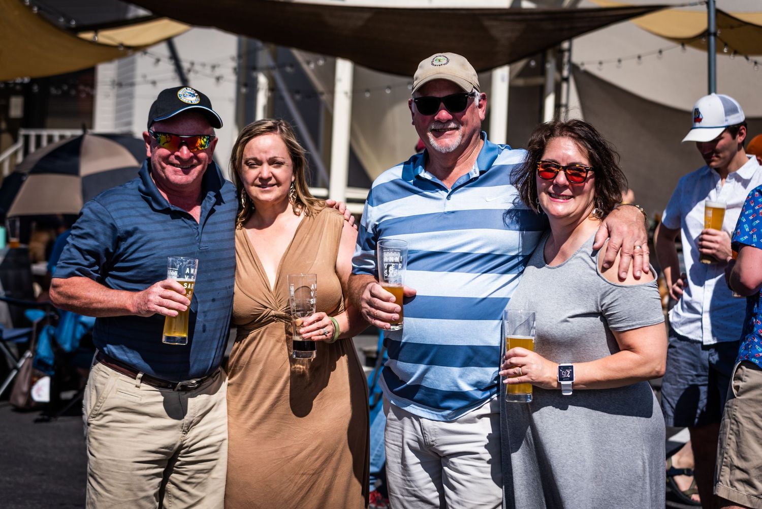 Friends enjoying craft beers together at outdoor brewery event.