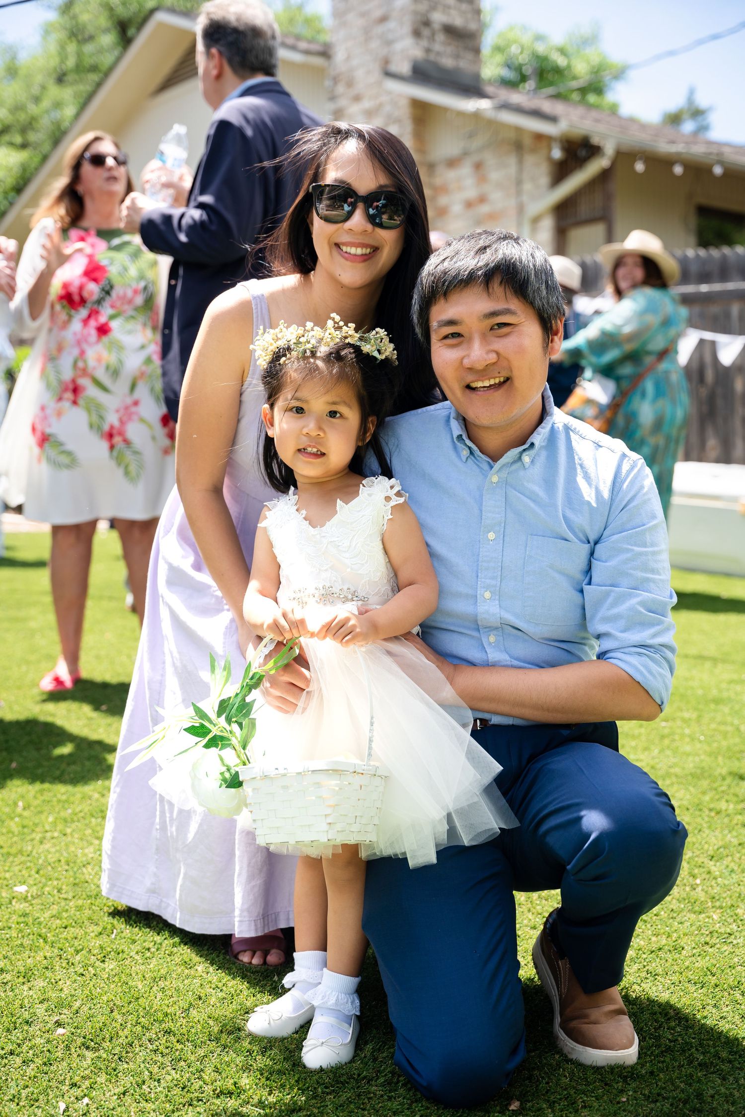 Family dressed in formal attire posing together on sunny lawn during celebration.