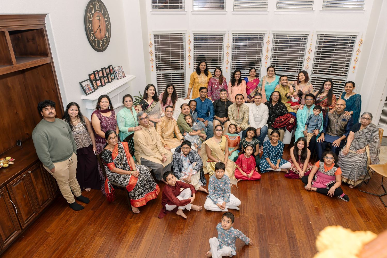 Large group dressed in traditional Indian attire gathered for indoor celebration photo.