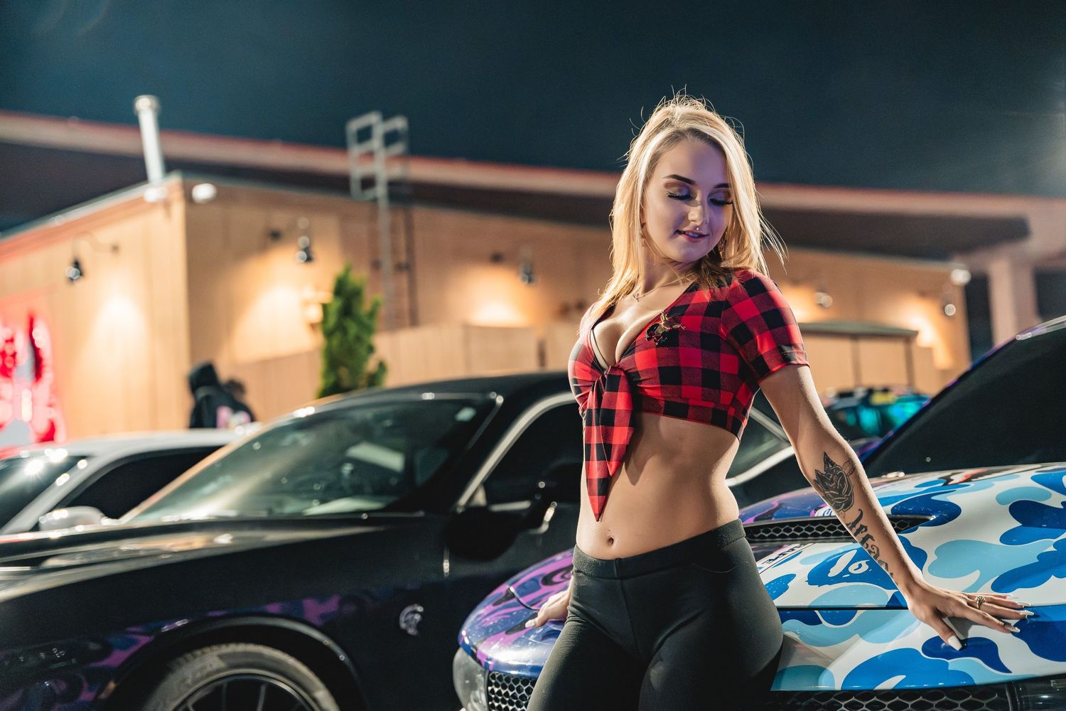 Cars displayed at a nighttime automotive gathering in a parking lot.
