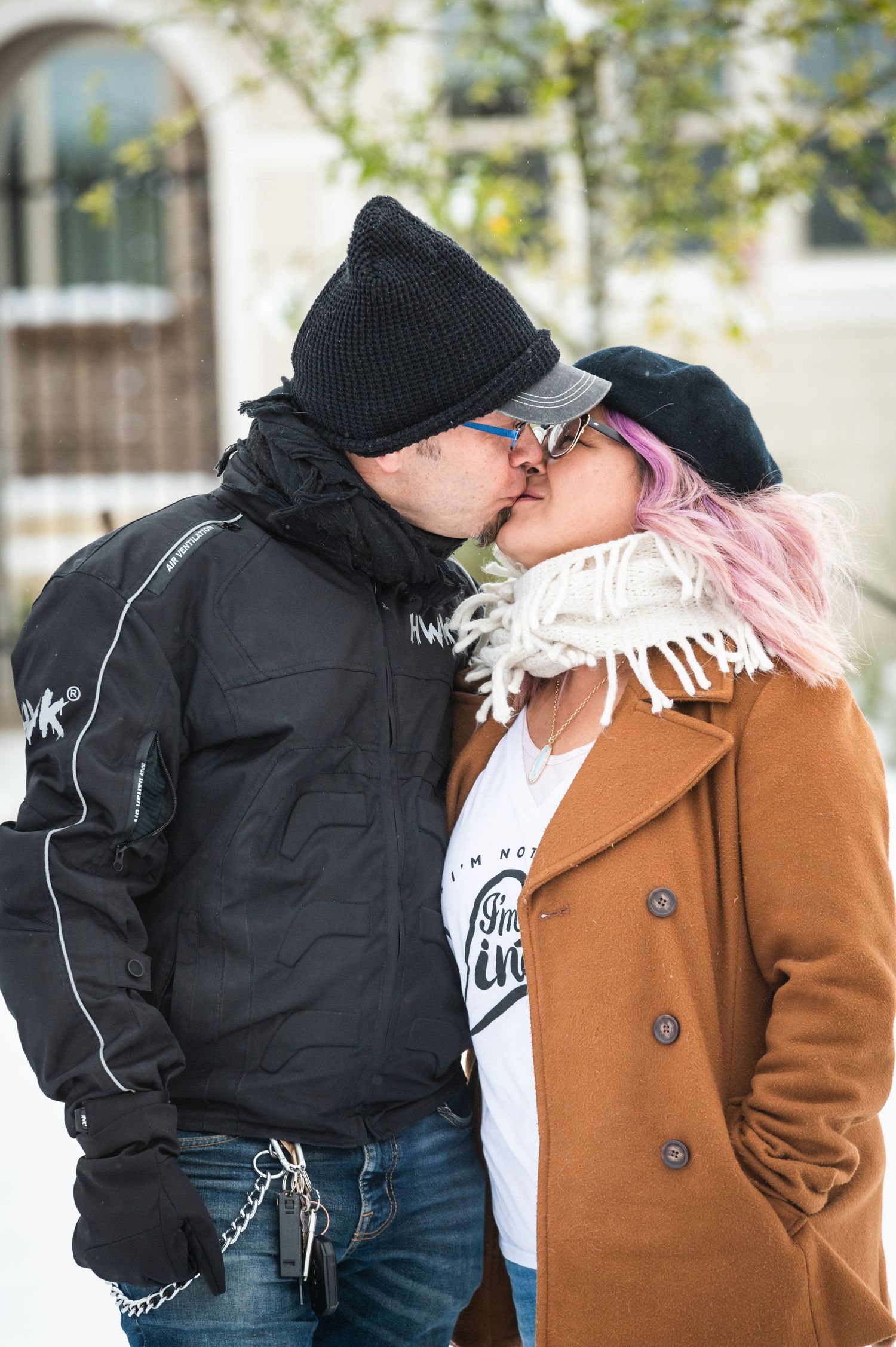 A couple in winter attire share an intimate moment outside on a cold day.