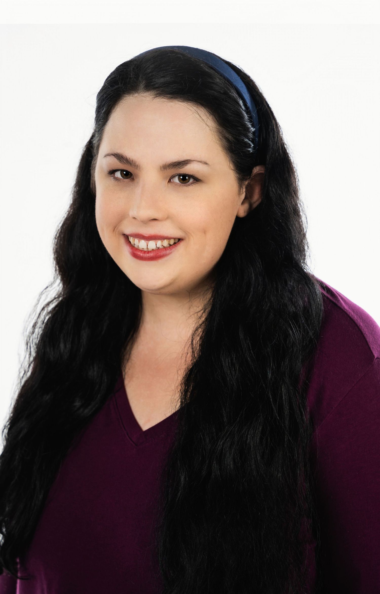 Professional headshot against white background featuring dark hair and blue headband.