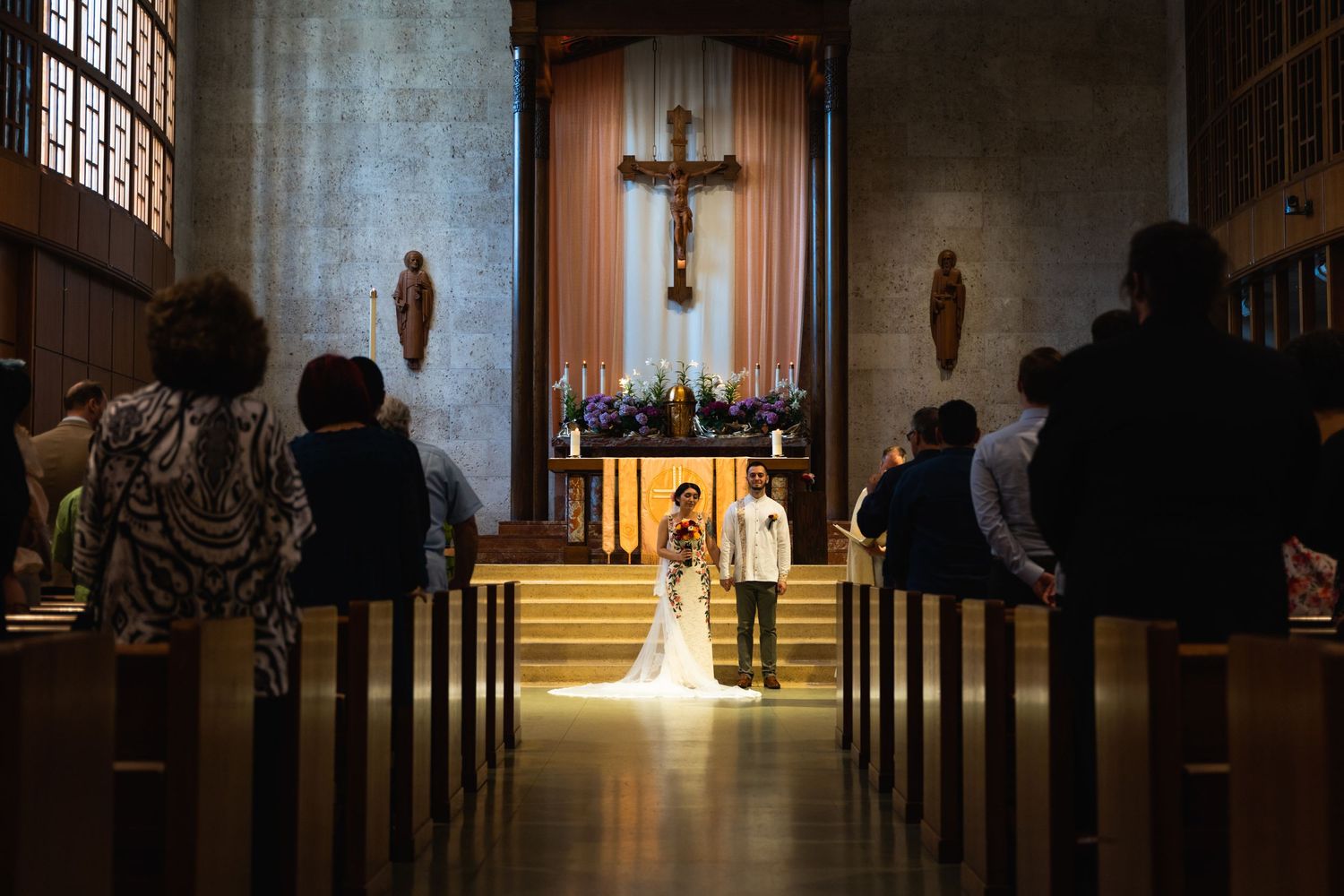 A church wedding ceremony with sunlight streaming through windows illuminating the aisle.