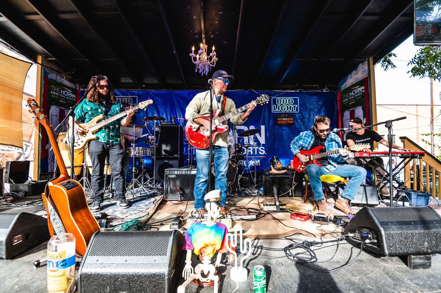 Band performs on outdoor stage with multiple instruments and equipment visible.