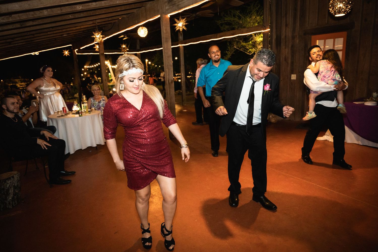 People dancing and celebrating on a wooden dance floor at an evening reception.
