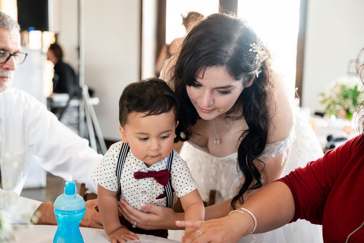 Family working together on paper crafts and activities at a bright white table with various creative supplies spread out.