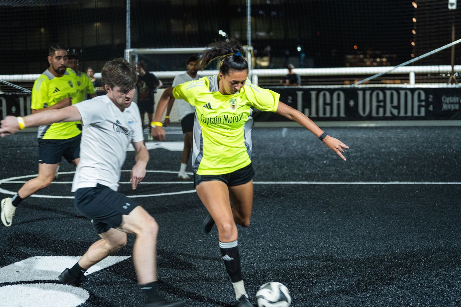 Players competing for the ball during an intense soccer match on artificial turf.