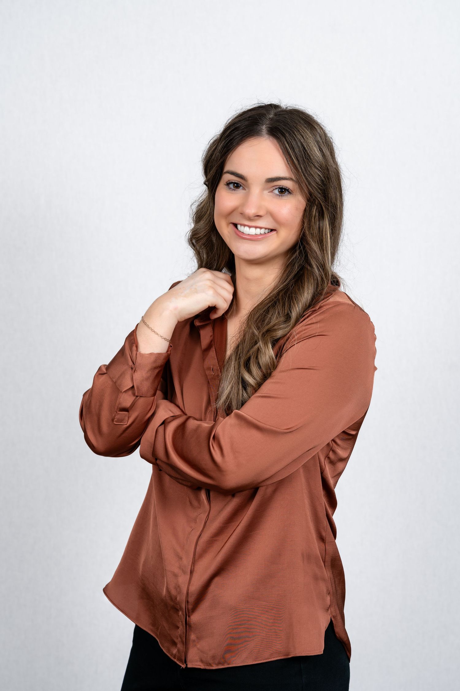 Professional headshot of a person in rust-colored blouse smiling warmly at camera.