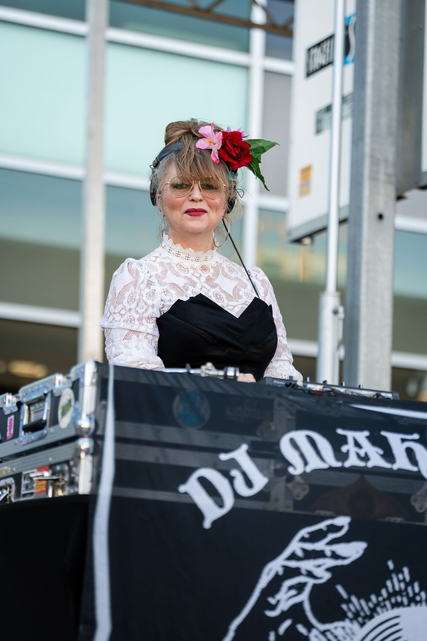 DJ setup with equipment and decorative signage at outdoor event.