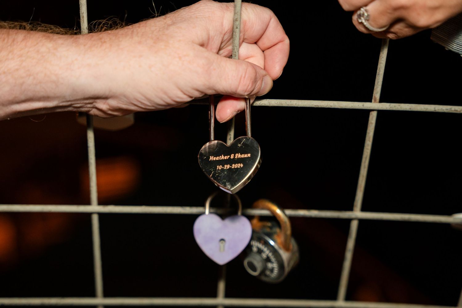 Close-up of love locks being attached to a metal railing.