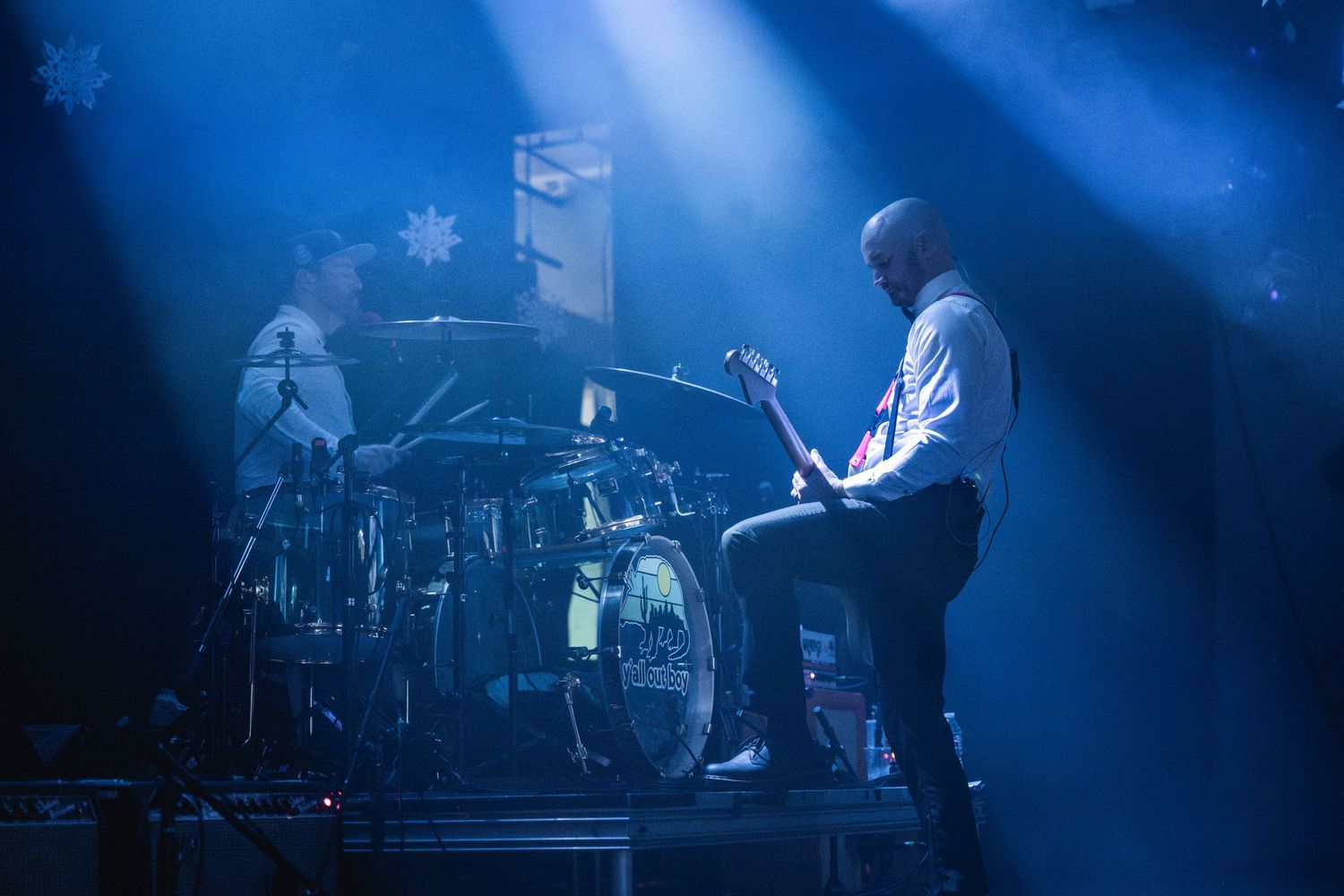 Band performing on stage bathed in atmospheric blue lighting with drum kit visible.