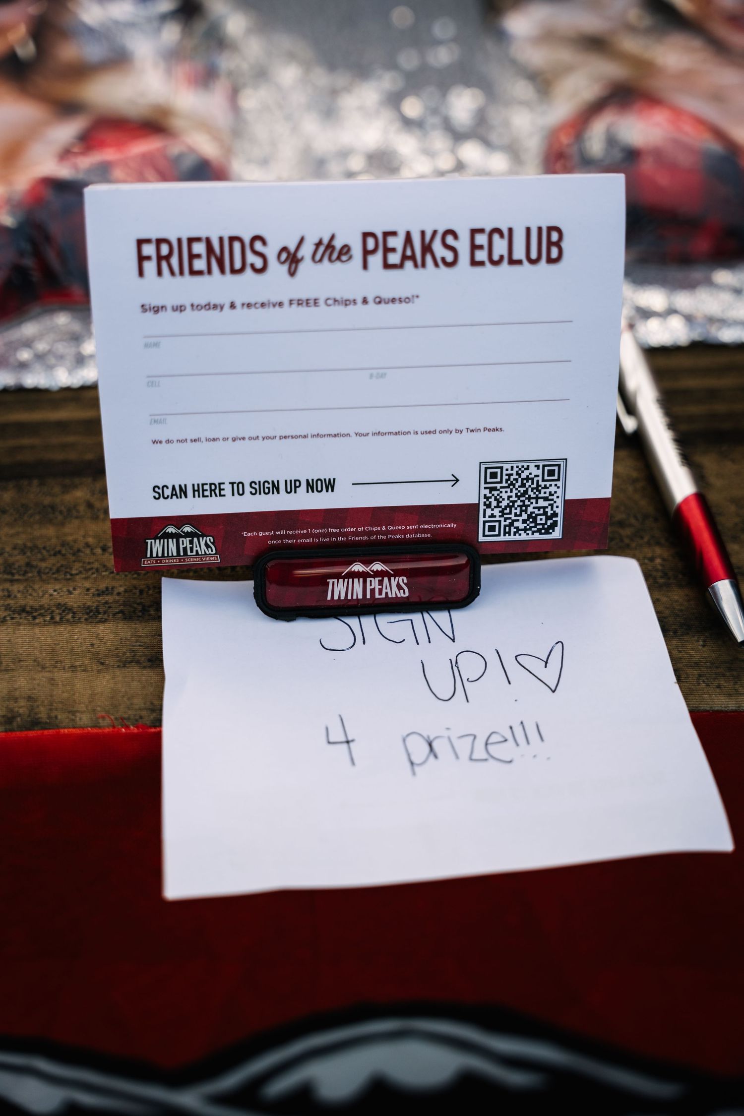 Sign up form for Friends of the Peaks Club membership with QR code on wooden surface.