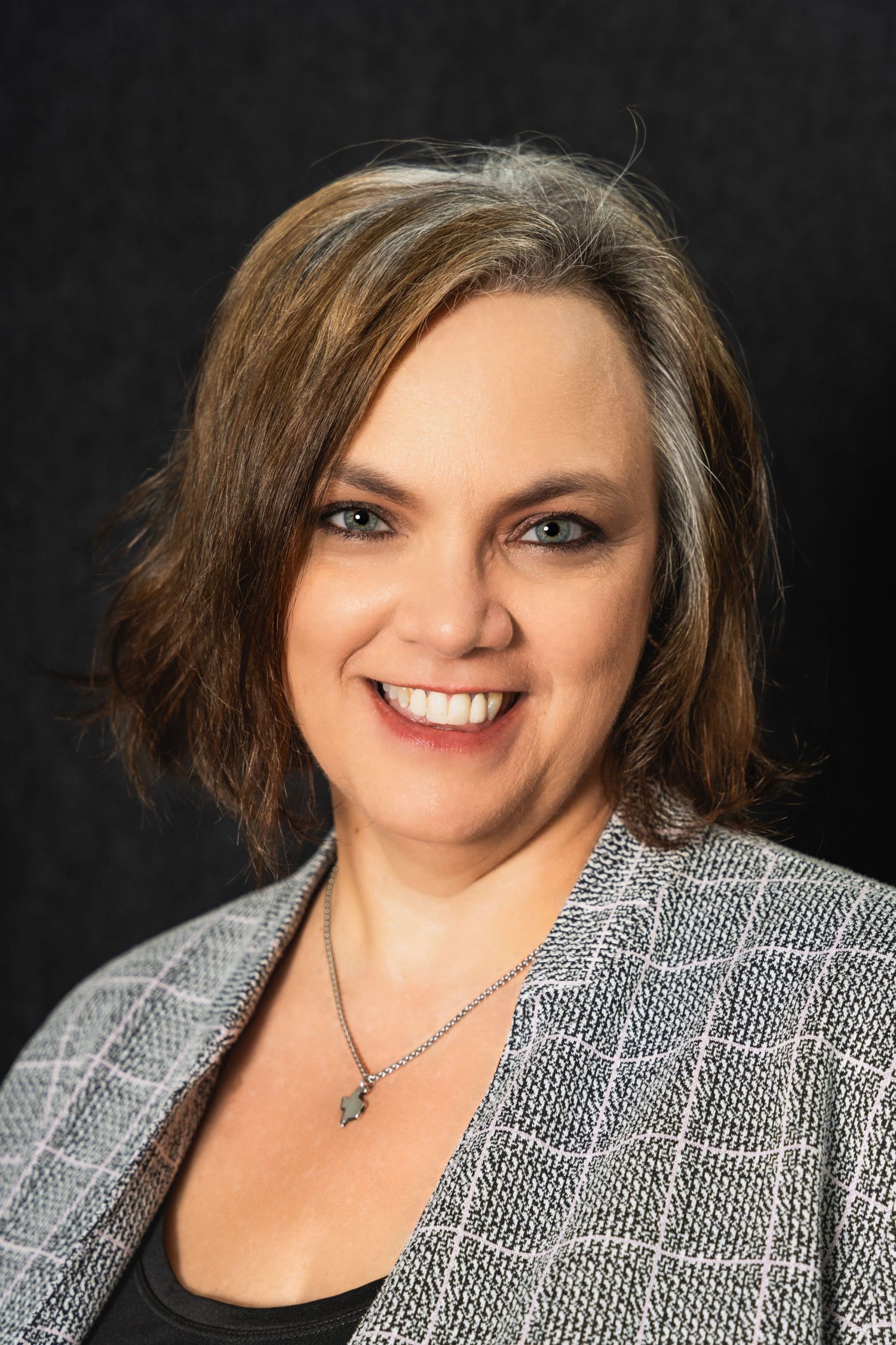 Studio portrait showcasing professional business attire and confident expression against dark backdrop.