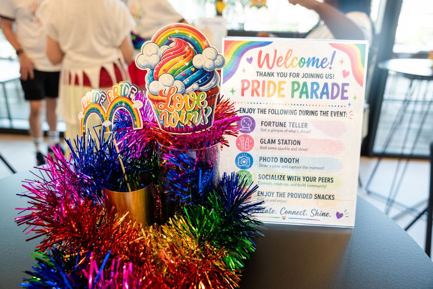 Colorful Pride Parade welcome sign with rainbow decorations and tinsel at a festive LGBTQ+ celebration event.