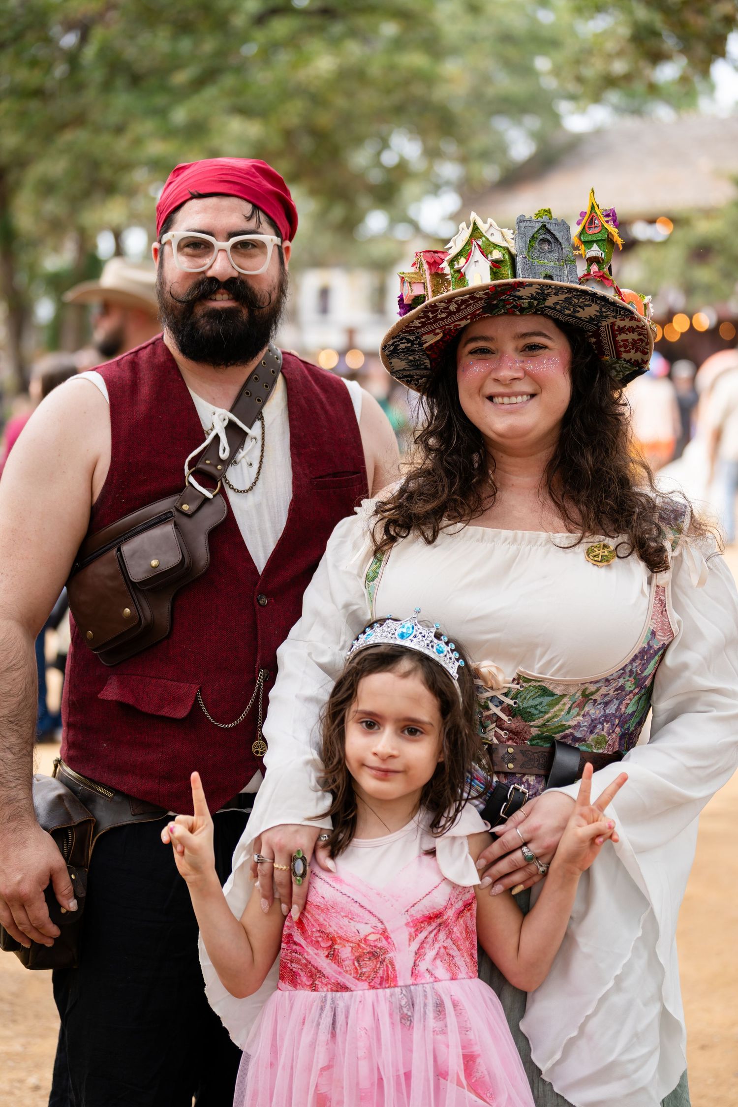 A group of people in Renaissance fair costumes pose together at an outdoor festival.