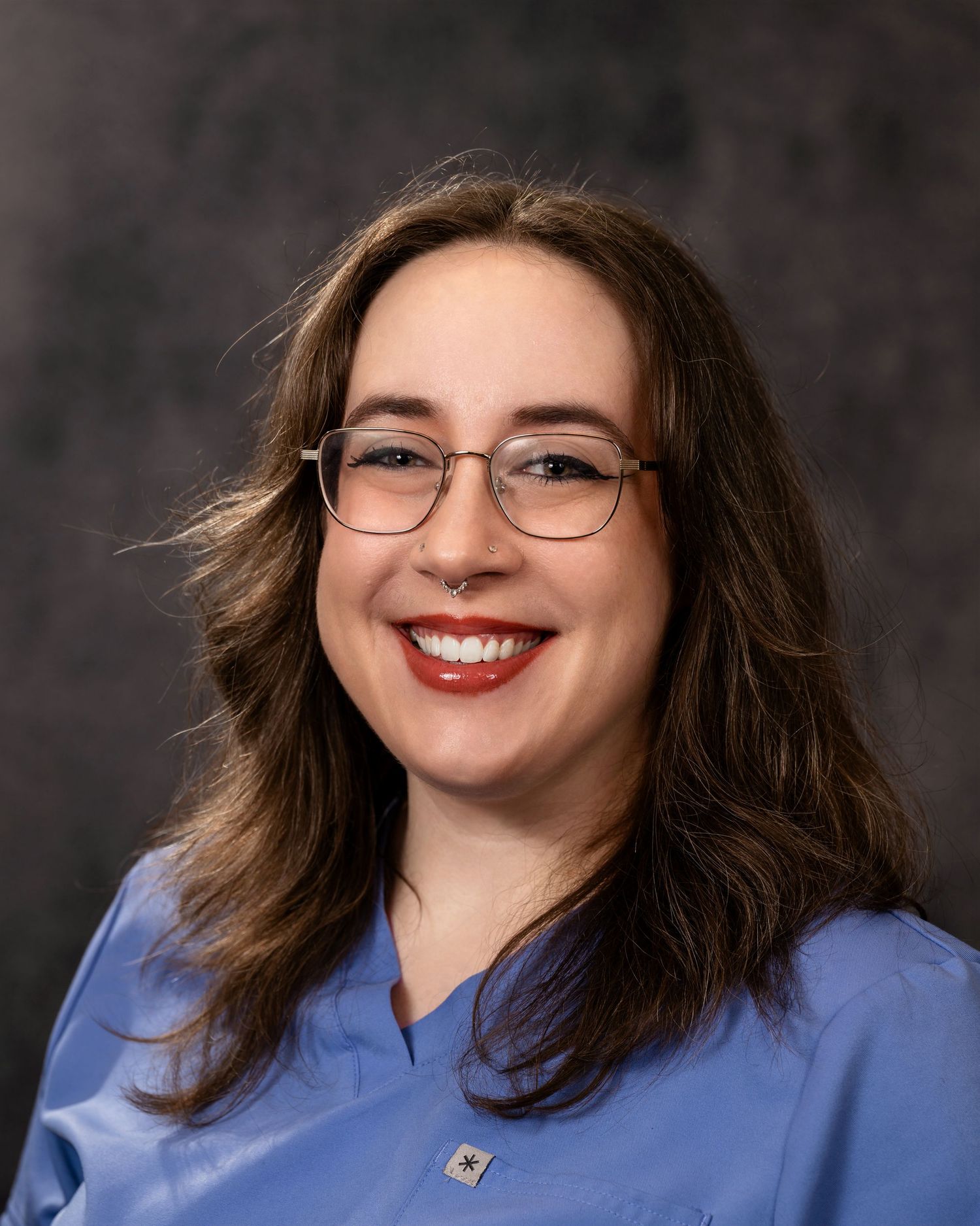 Person in glasses and blue shirt smiling warmly in a series of professional headshots against dark background.
