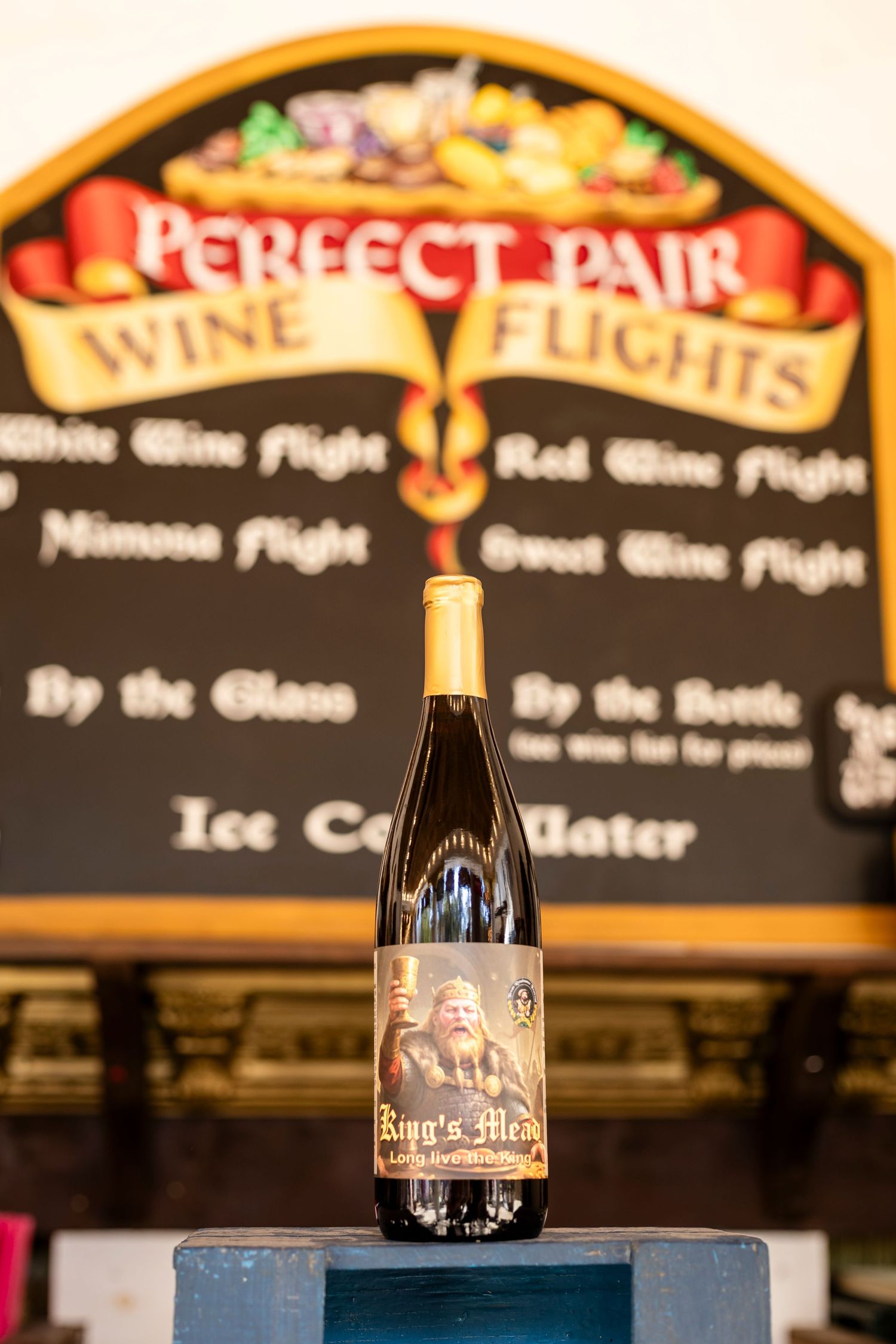 Beer bottles displayed against a dark background with illuminated menu boards showing wine and drink selections.