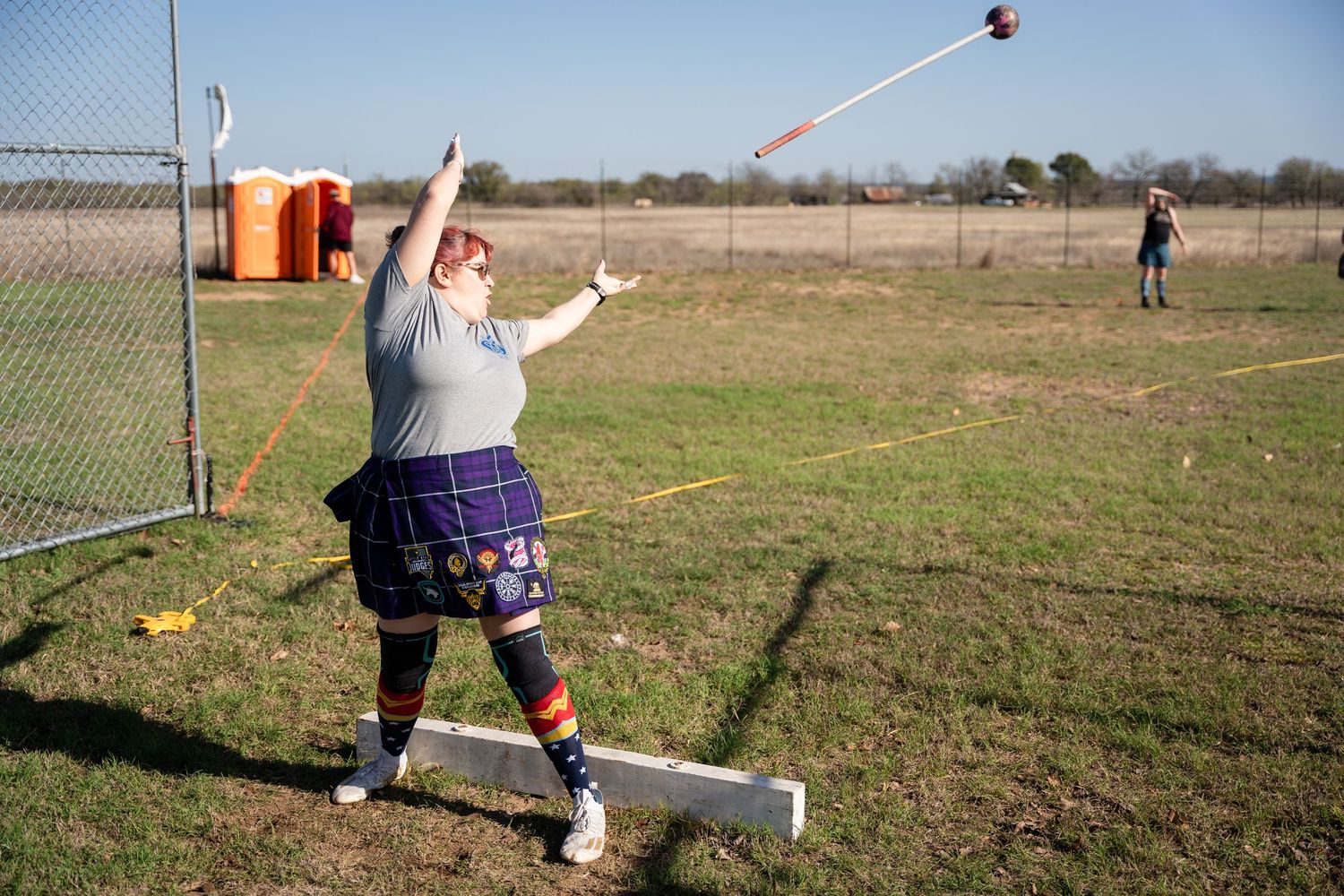 Athlete throwing a hammer in a field during a track and field competition outdoors.