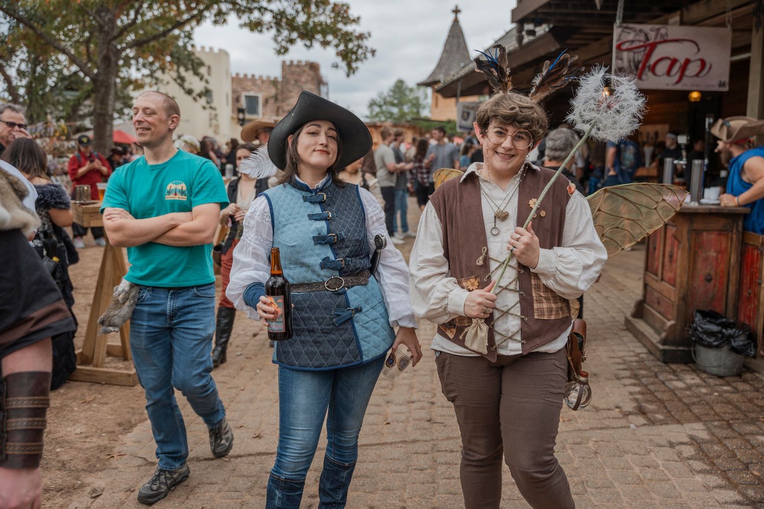Festival attendees in period costumes walking along marketplace path.