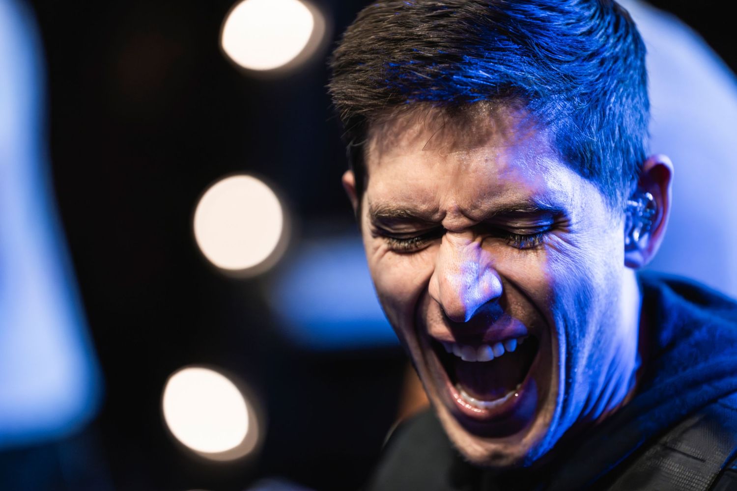 Performer on stage captured in expressive moment under blue stage lighting.