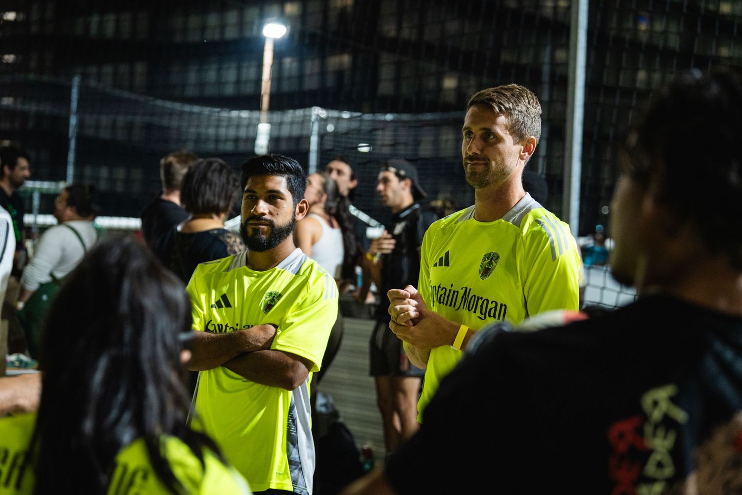 Players in neon yellow jerseys gathered during a nighttime sporting event.