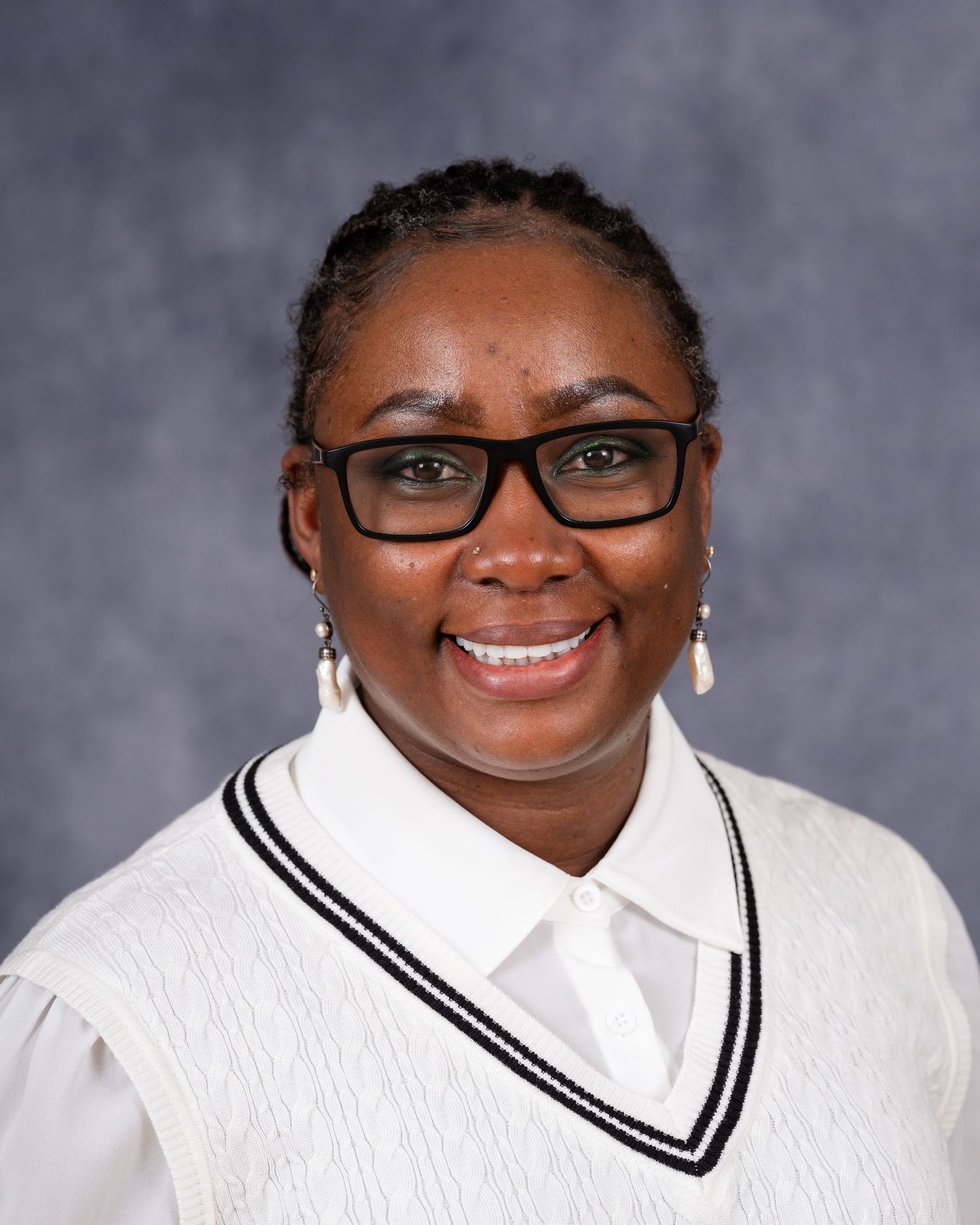 Professional portrait of a person in white v-neck sweater with glasses against gray background.