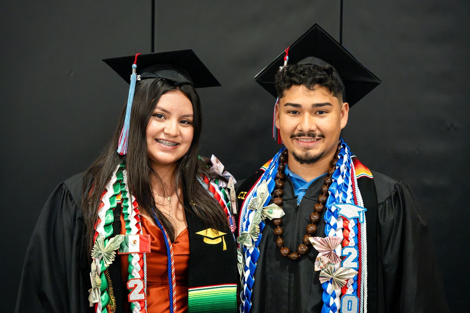 Graduates wearing colorful stoles and traditional black caps and gowns at commencement.