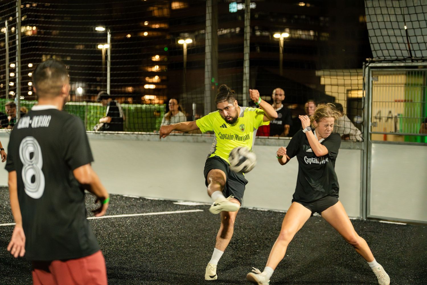 Soccer players compete intensely with yellow and black uniforms on indoor court.