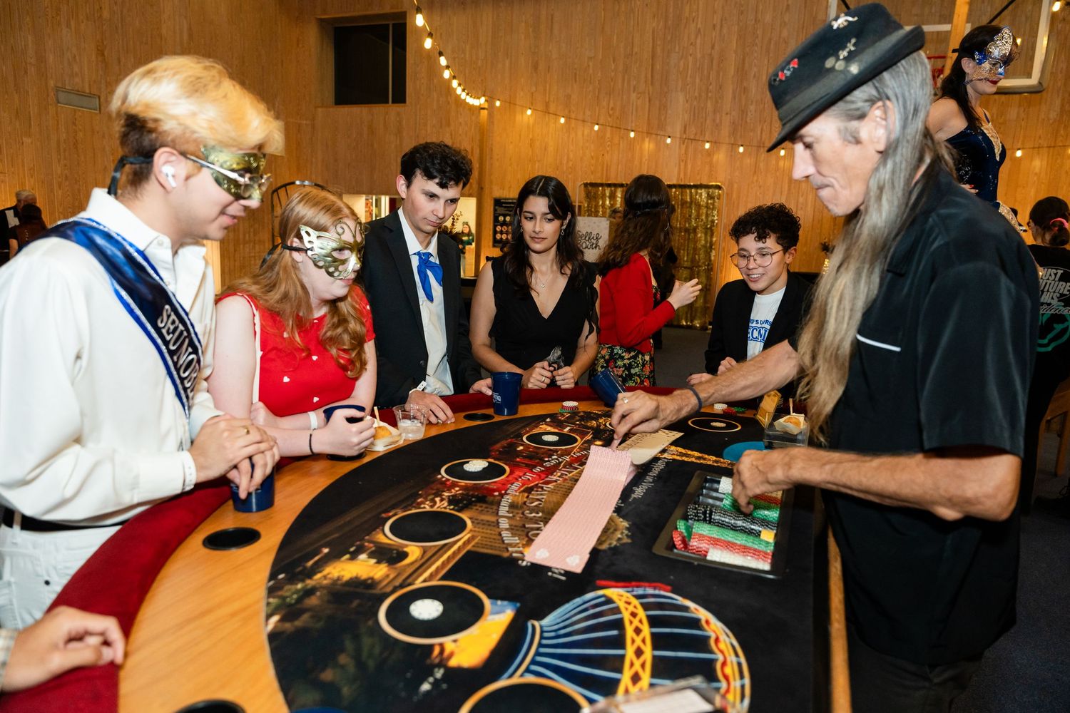 Dealers and players interact at a casino gaming table during a themed event.