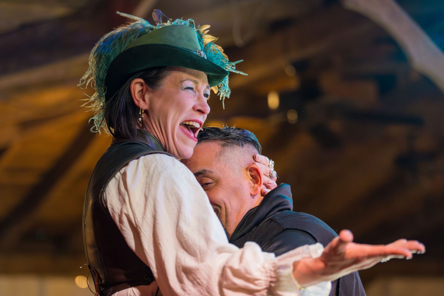 Two performers sharing a joyful moment during a medieval-style theatrical performance.