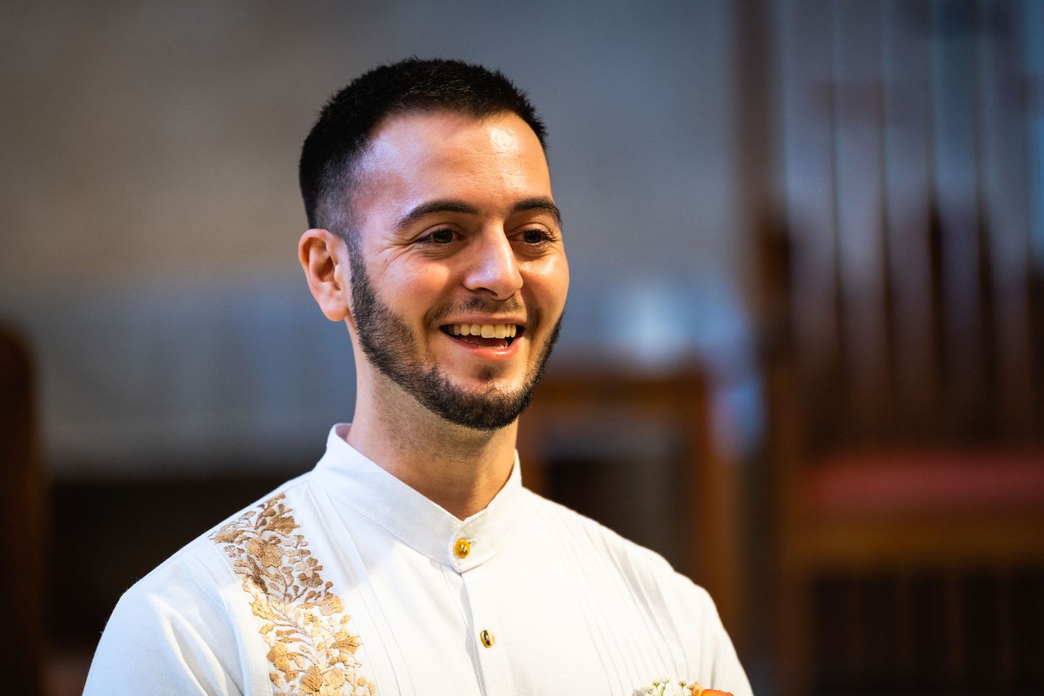 Participant in wedding ceremony wearing traditional white and gold attire.