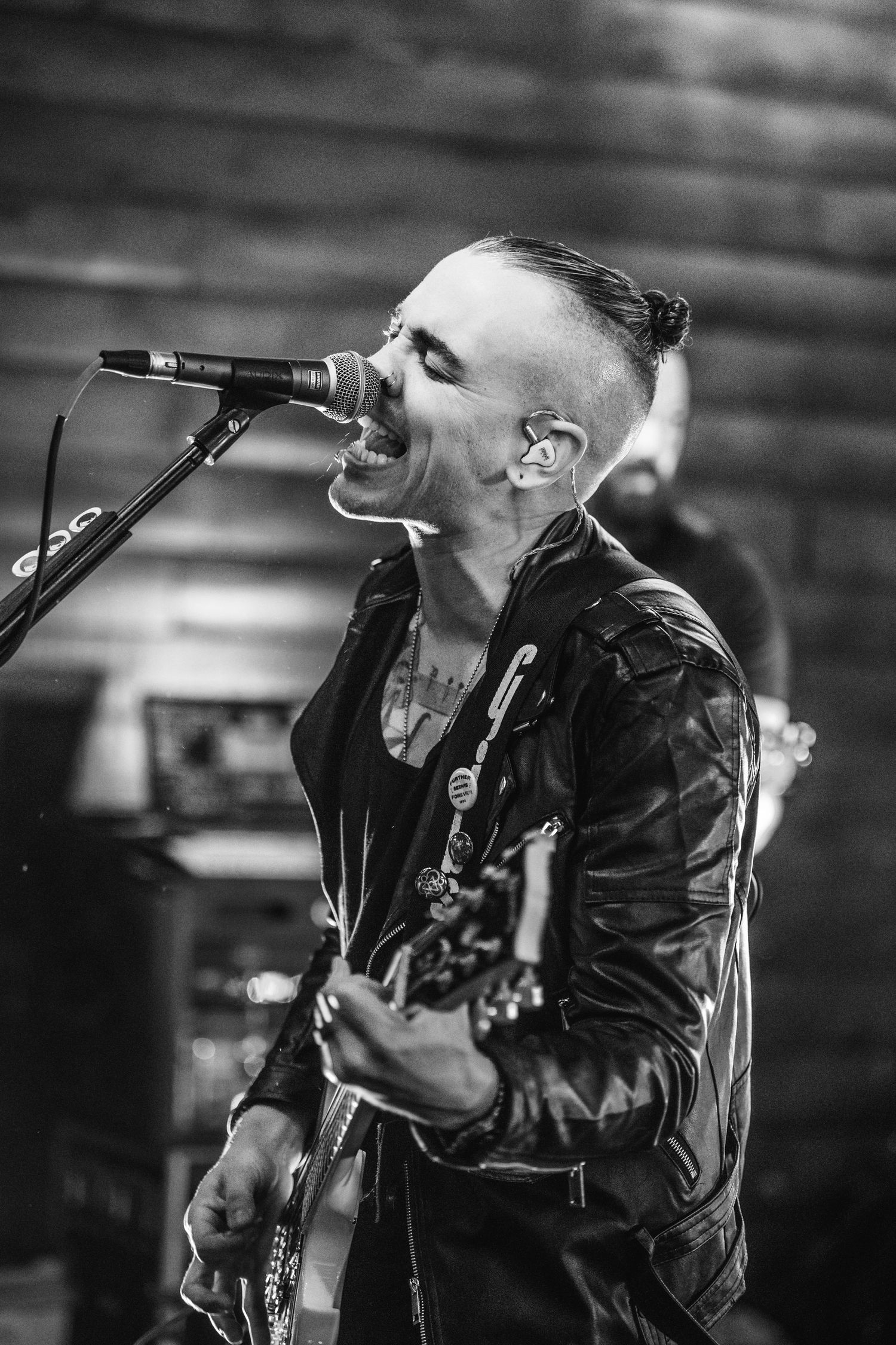 Black and white photo of musician singing and playing guitar on stage.