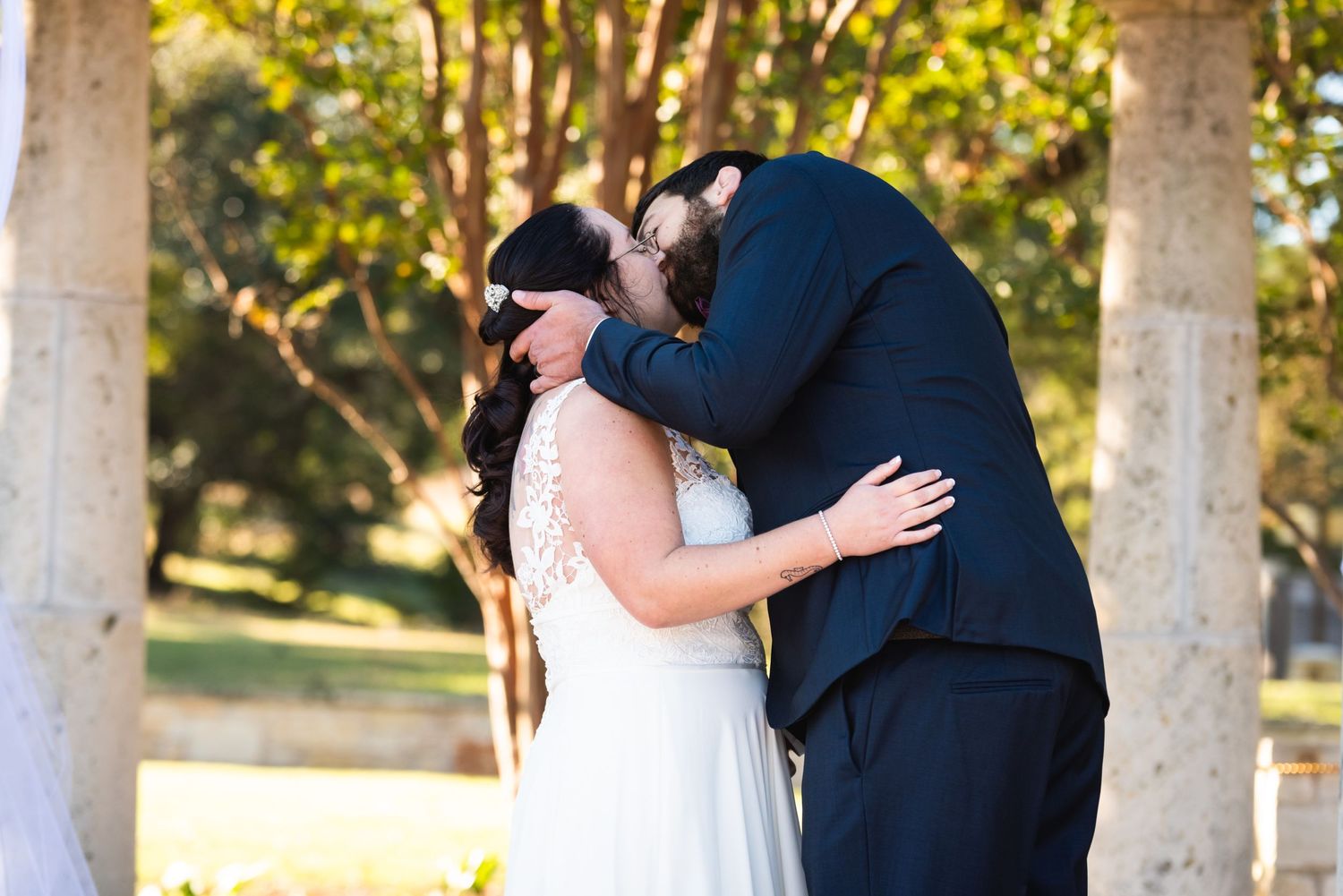 Newlyweds share their first kiss as a married couple during outdoor wedding ceremony.
